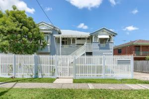 a blue house with a white picket fence at Experience this Stylish Brisbane Apartment in Brisbane