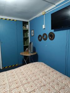 a blue room with a bed and a table at QUELKUN, FAMILIAR in Quellón