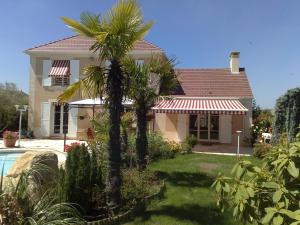 una casa con una palmera en el patio en Villa Cendrillon, en Magny-le-Hongre