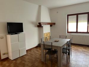 a dining room with a table with chairs and a tv at Casa del Faggio Rosso in Bellagio