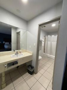 a bathroom with a sink and a toilet and a mirror at Portside Inn & suites in San Pedro