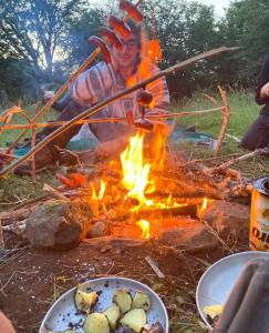Ferme Equestre des Esprits Sauvages في Prades-dʼAubrac: رجل يجلس حول النار المخيم مع الطعام