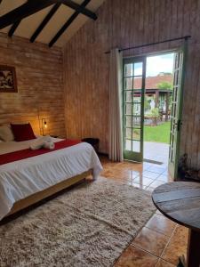 a bedroom with a bed and a sliding glass door at Pousada Brisa da Mantiqueira in Monte Verde