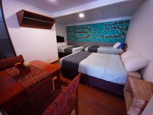 a hotel room with two beds and a table and chairs at Valle verde, Hostel & camping in Urubamba