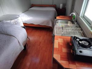 um pequeno quarto com duas camas e um fogão em Hostal Saint Michell. El Quisco em El Quisco