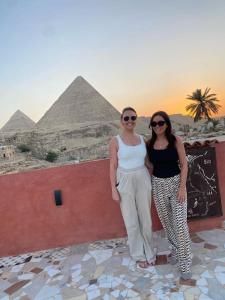 twee vrouwen die naast een muur met piramides staan bij El Khalil Pyramids Inn in Caïro