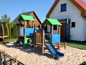 a playground in the sand in front of a house at Domki wakacyjne 4 YOU in Ustka