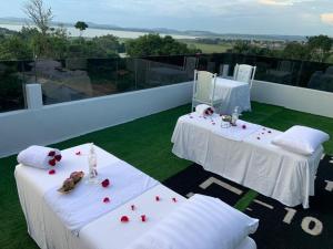 two white tables with red roses on a balcony at El Amo Lakeview villa in Entebbe