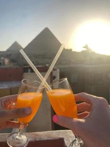 twee mensen met een glas sinaasappelsap met rietjes bij El Khalil Pyramids Inn in Caïro