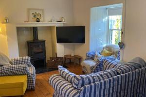 un salon avec des canapés, une cheminée et une télévision dans l'établissement Christmas Cottage, à Balmaha
