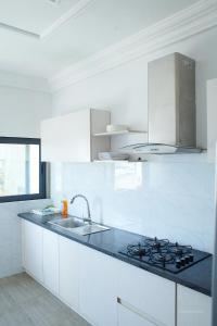 a white kitchen with a sink and a stove at Le VÏU2 in Cotonou