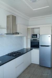 a kitchen with white cabinets and a white refrigerator at Le VÏU2 in Cotonou