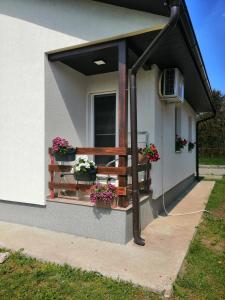 uma casa com uma varanda com flores e uma janela em Kuća za odmor Jovana&Ivona 2023 OBRADOVIĆ SOKAK 41 em Šimanovci