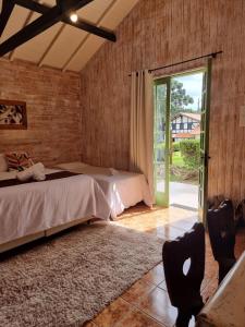 a bedroom with two beds and a sliding glass door at Pousada Brisa da Mantiqueira in Monte Verde
