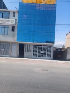 a building with a blue glass facade next to a street at Big blue house in Chimbote