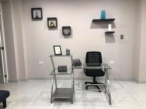 a glass desk with a chair and pictures on a wall at Big blue house in Chimbote