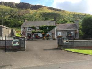 a house with a gate and a mountain in the background at Tamlaught house in Glenariff