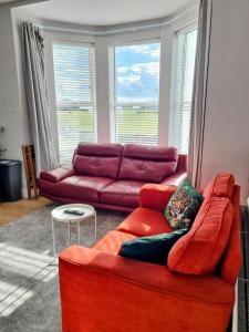 a living room with a red couch and a table at Portrush by the Sea - 3 West Beach in Portrush