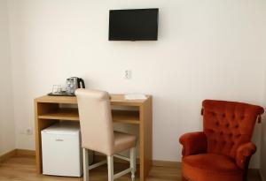 a desk with a chair and a television on a wall at Nova Delpa AL in Caldas da Rainha