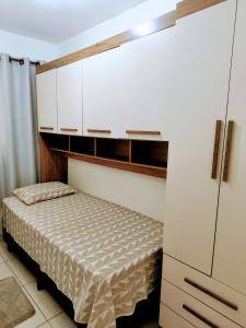 Dormitorio pequeño con cama y armarios blancos en Apartamento em Condomínio fechado., en Itatiba