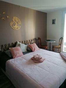 ein Schlafzimmer mit einem großen weißen Bett mit rosa Kissen in der Unterkunft La Maison des Amis in Les Essarts