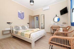 a bedroom with a bed and chairs and a tv at Niko's Beach Suites ΕΝΑ in Agia Marina Aegina