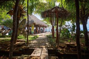 a path with umbrellas and a surfboard on a beach at Finca Popoyo in Popoyo