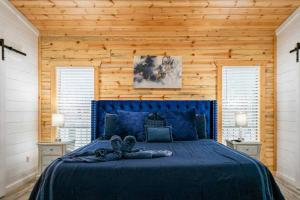 a bedroom with a blue bed and wooden walls at Diamond Cabin w/ jet shower & secluded back deck! in Broken Bow