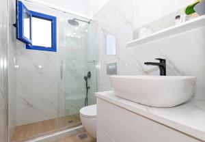 a white bathroom with a sink and a shower at Niko's Beach Suites ΕΝΑ in Agia Marina Aegina