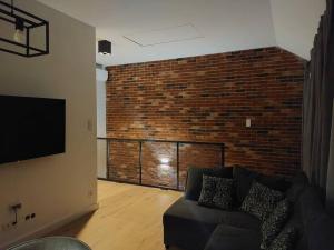 a living room with a couch and a brick wall at Apartament z dużym tarasem in Kraków