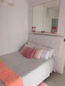 1 cama con almohadas rosas y blancas y espejo en Casa Yurena, en Playa Honda