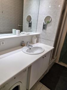 ein weißes Badezimmer mit einem Waschbecken und einem Spiegel in der Unterkunft Charmant triplex familial au coeur du Pouliguen, proche de la plage et de la Baule in Le Pouliguen