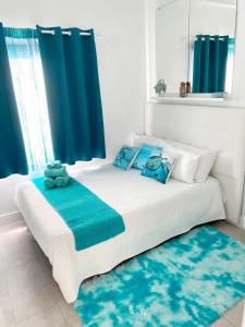 Cama blanca con almohadas azules y cortinas azules en Casa Yurena, en Playa Honda