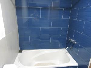 uma casa de banho com azulejos azuis e uma banheira branca em Ribera Parana Suit em Rosário