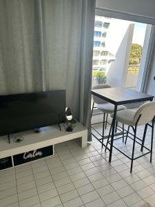 un soggiorno con TV, tavolo e sedie di Studio première ligne mer parking a La Grande-Motte Altre 15 foto