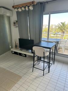un tavolo nero con sedie in una stanza con finestra di Studio première ligne mer parking a La Grande-Motte