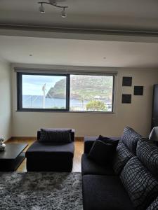 a living room with a couch and a large window at VIP Paradise Apartment in Machico