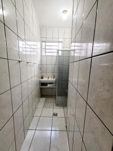 a bathroom with white tiled walls and a sink at Suíte Proença in Campinas