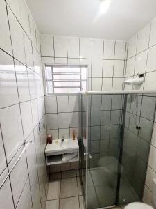 a bathroom with a glass shower and a sink at Suíte Proença in Campinas