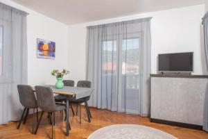 jadalnia ze stołem i krzesłami oraz telewizorem w obiekcie Apartments Lovric with sea view w mieście Kaštela