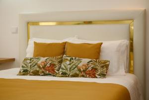 uma cama com uma cabeceira branca e algumas almofadas em Nova Delpa AL nas Caldas da Rainha
