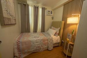 Scarlet Suites Condominium في Babak: غرفة نوم صغيرة بها سرير ومصباح
