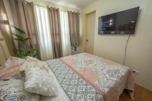 a bedroom with a bed and a flat screen tv at Scarlet Suites Condominium in Babak