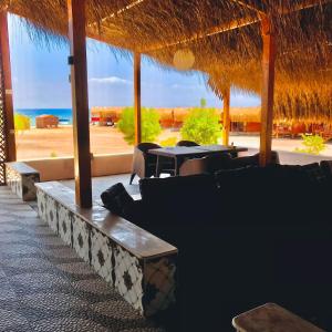 塔巴的住宿－Sayal Camp，一间带桌椅和海滩的餐厅