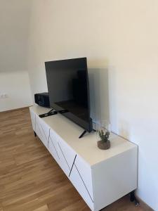 a flat screen tv sitting on top of a white cabinet at Apartments Fast Food Bodensdorf in Feldkirchen in Kärnten