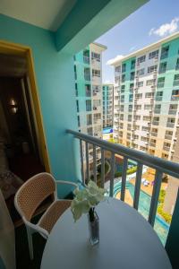 una mesa con un jarrón de flores en el balcón en Scarlet Suites Condominium en Babak