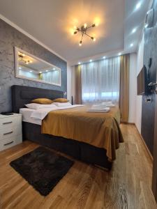 - une chambre avec un grand lit et un miroir dans l'établissement LUX APARTMENT SANJA 3, à Subotica