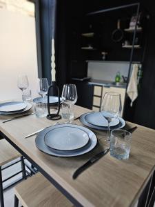 - une table en bois avec des assiettes et des verres à vin dans l'établissement BLACK BOX CINEMA appartement avec balnéo, à Épinal