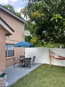 eine Terrasse mit einem Tisch, Stühlen und einem Sonnenschirm in der Unterkunft NEW Designed Apt 2023 NrUCF PETSOk PrivateEntry in Orlando