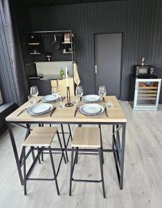 - une table avec des chaises, des assiettes et des verres à vin dans l'établissement BLACK BOX CINEMA appartement avec balnéo, à Épinal